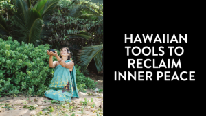 A Hawaiian woman in a floral pareo meditates peacefully on the sand overlooking the ocean in Hawaii.